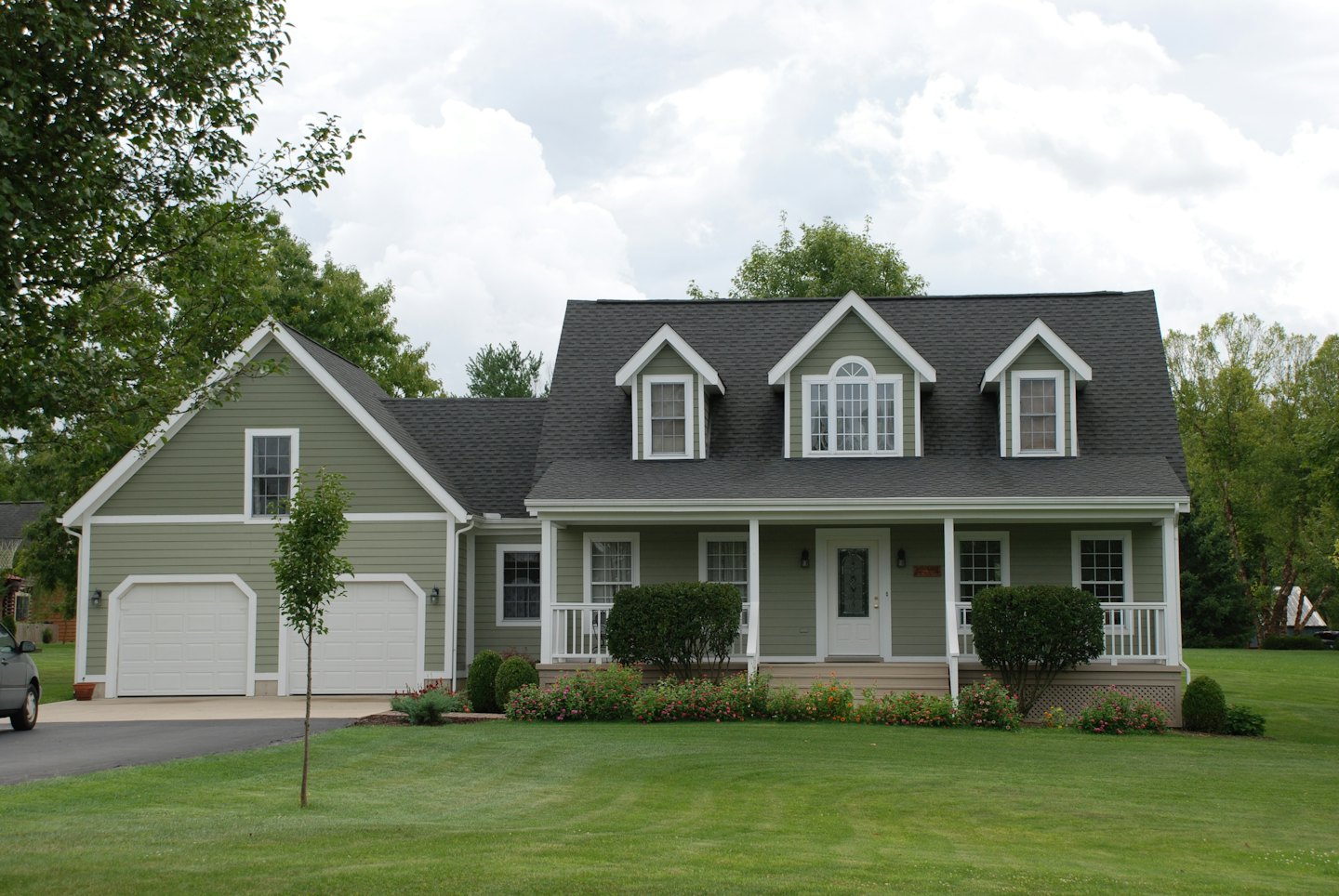 Suburban house with green siding and a white-railed porch.