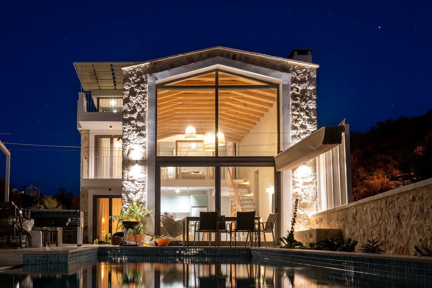 Modern villa at night with glowing windows and pool.