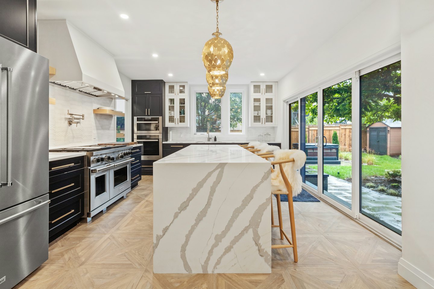 Modern kitchen with marble island and green backyard view.