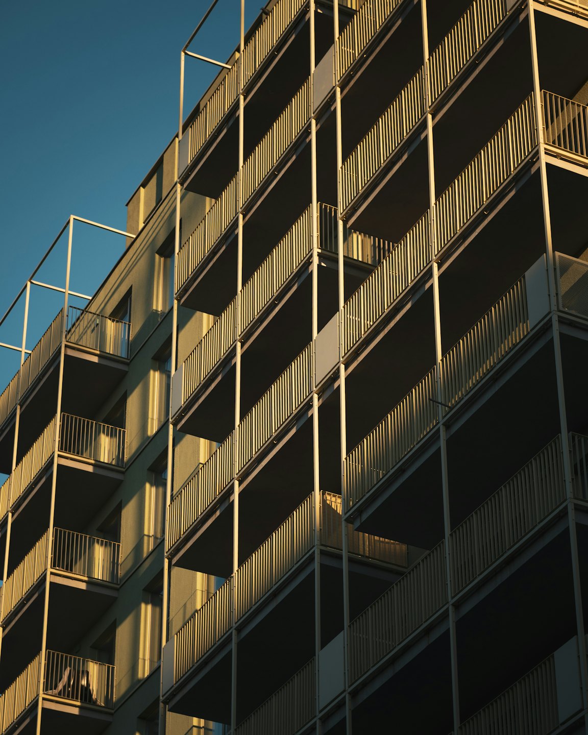 Modern apartment building with many balconies at golden hour.